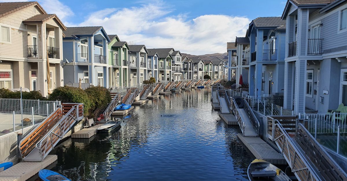 Row of colorful houses lining a tranquil canal in Sparks, Nevada, under a blue sky.