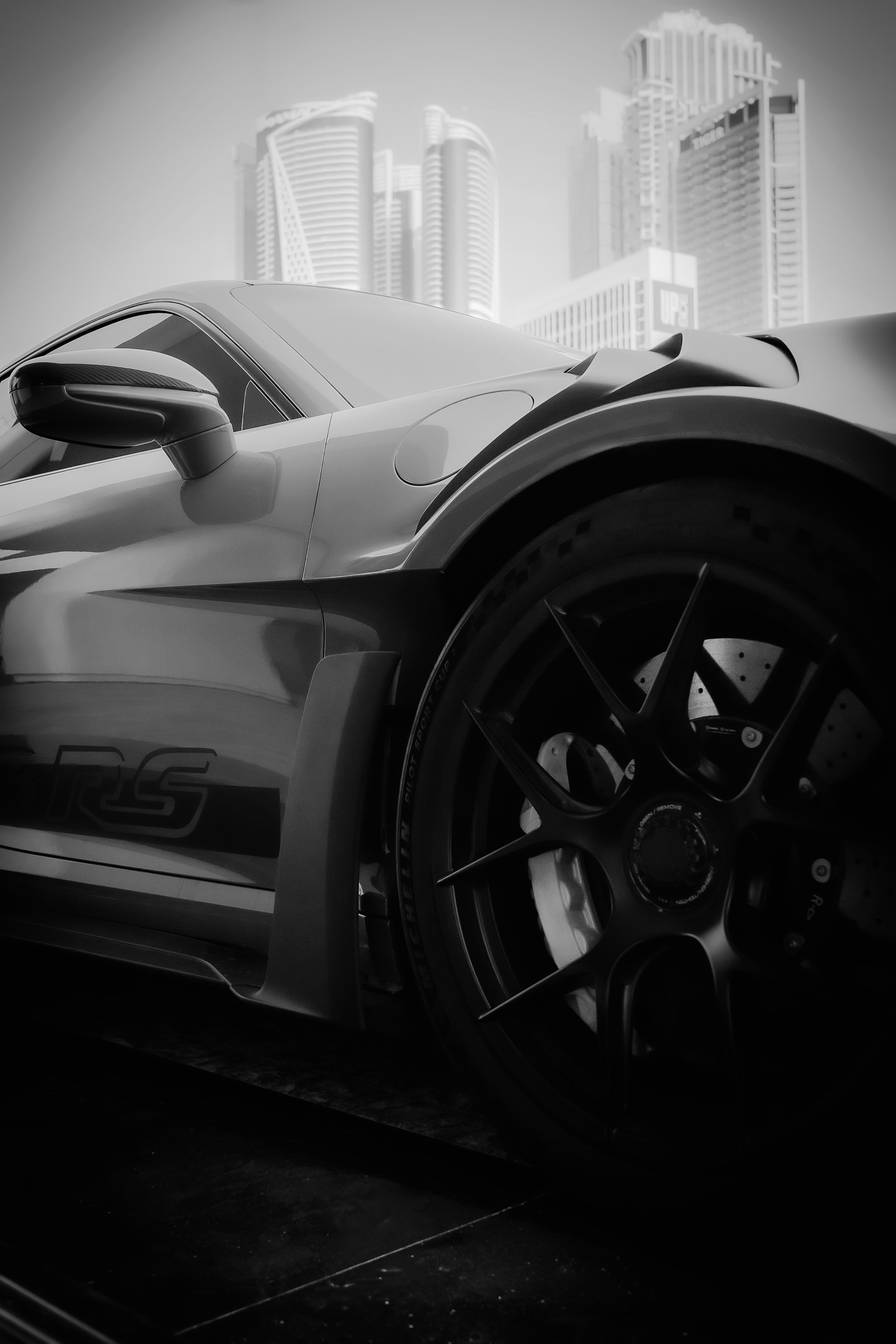 Close-up of a luxury car against the modern skyline of Dubai, United Arab Emirates.