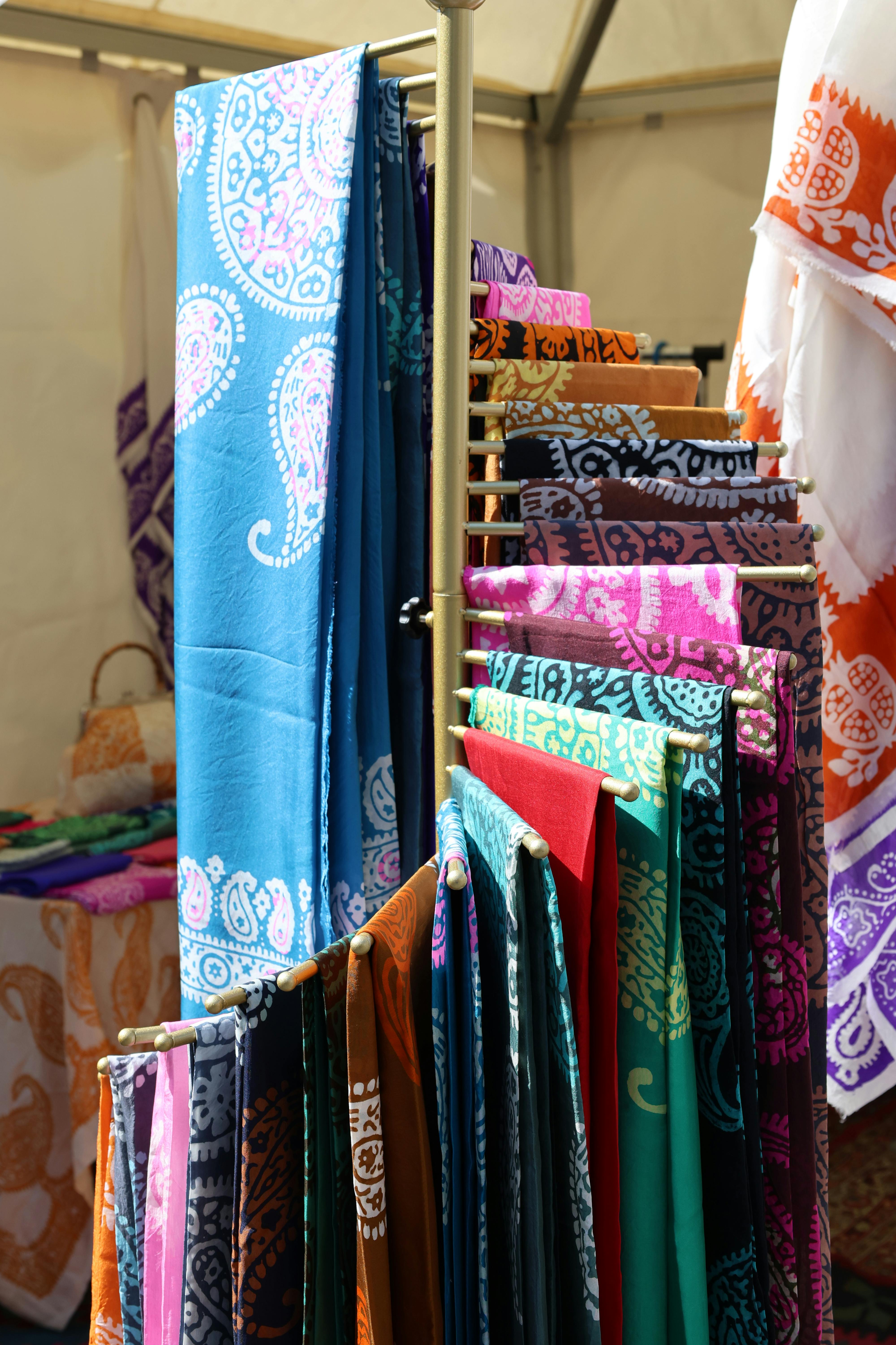 Folded hand-stamped Balinese batik sarongs in indigo, rust, and forest green at a traditional textile stall
