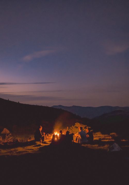 Free A group of people enjoying a campfire in a scenic outdoor setting during twilight. Stock Photo