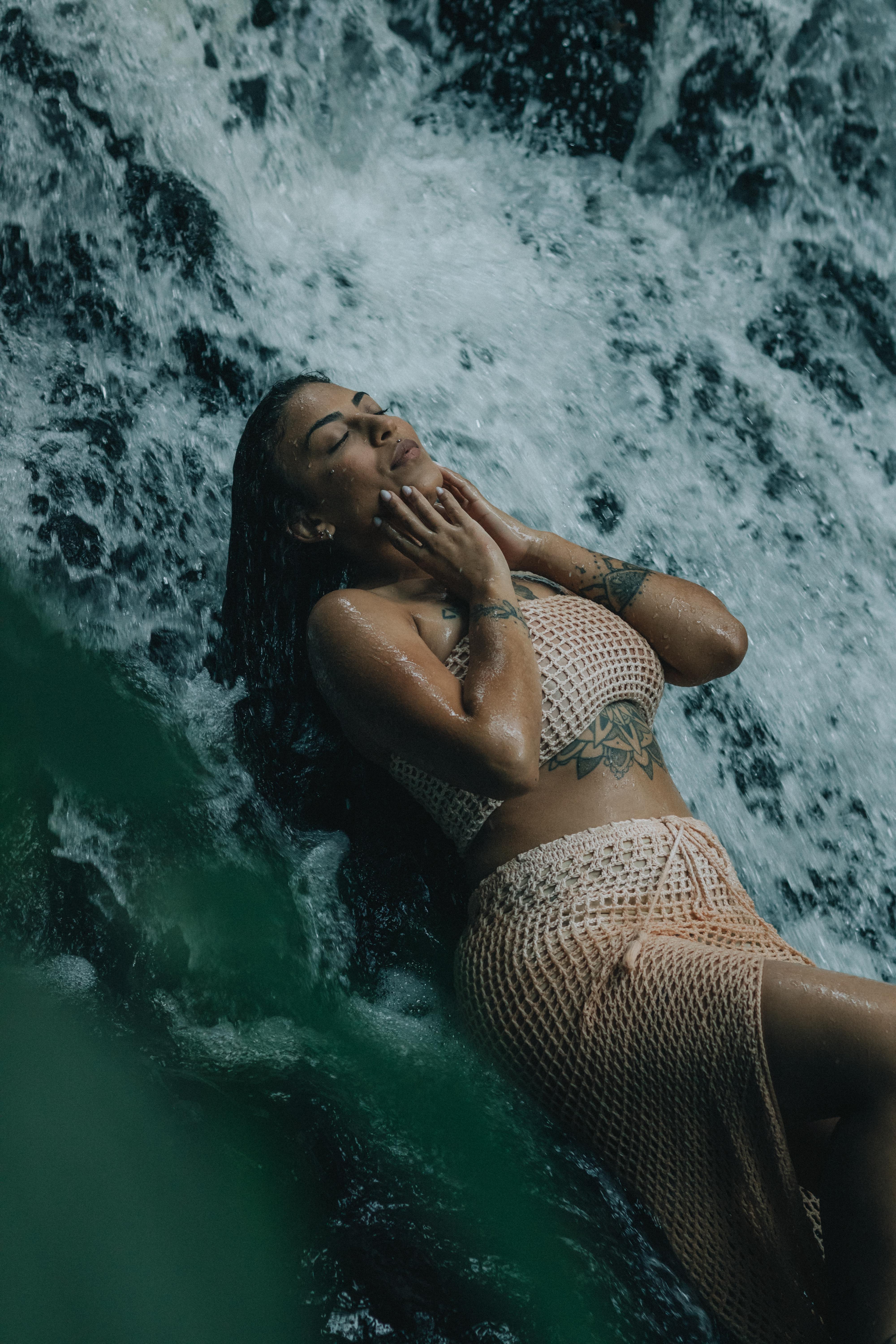 Serene image of a woman enjoying a rejuvenating moment under a waterfall.