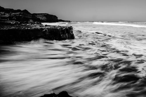 Free A moody black and white photograph capturing dramatic waves crashing against rocky cliffs. Stock Photo