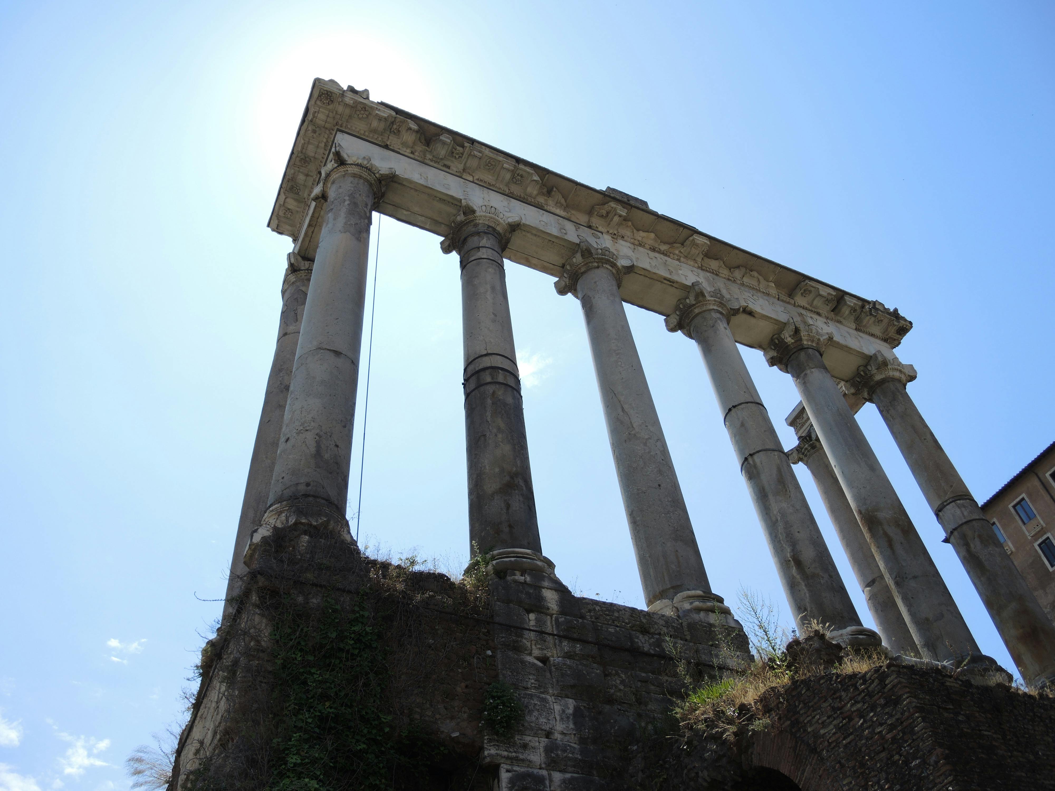 Ancient Roman temple columns reaching towards a clear blue sky, showcasing classical architecture.
