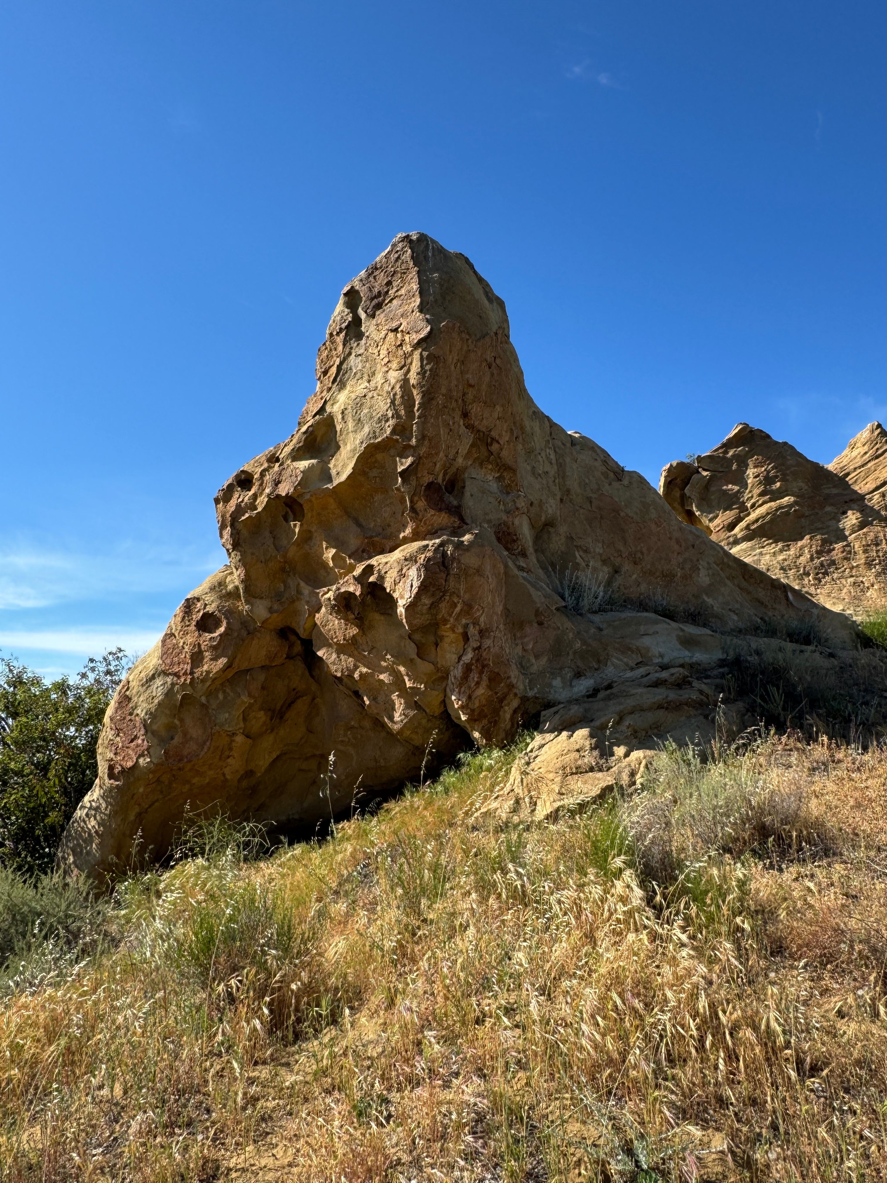 Dramatic rock formation in California's sunny landscape under a clear blue sky.