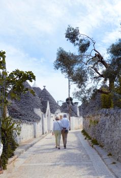 Couple strolling down a picturesque street in Alberobello with traditional trulli houses.