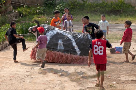 A group of children engaging in a traditional bull role-play game outdoors.