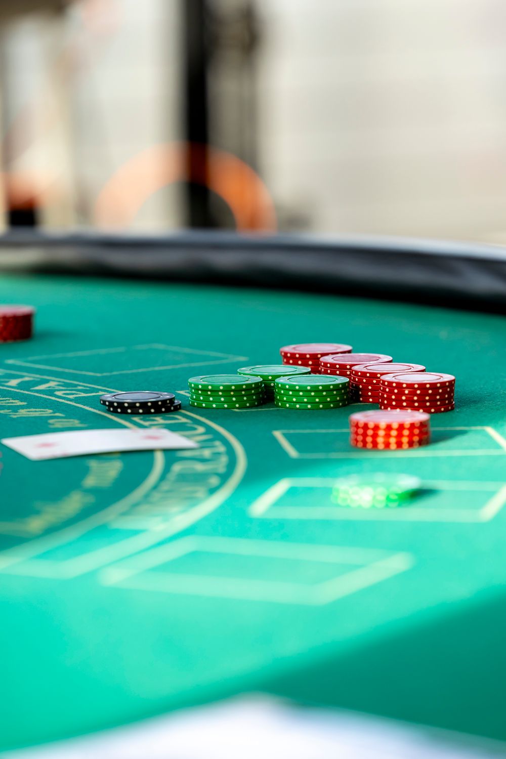 Colorful casino chips and playing cards laid out on a green blackjack table