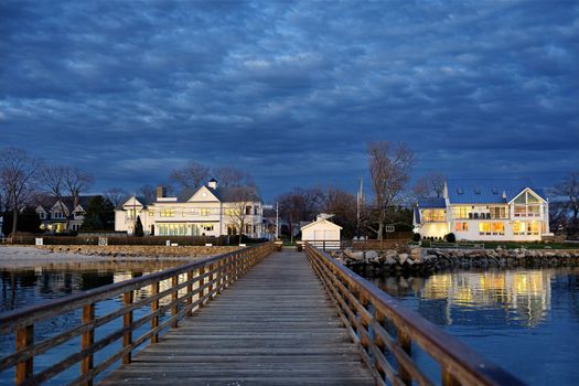 A tranquil pier extends into twilight, with waterfront homes glowing in Norwalk, Connecticut.