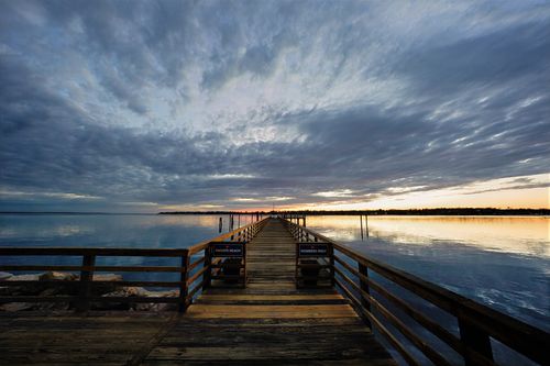 Free A breathtaking sunset view over a wooden pier in Norwalk, Connecticut, capturing the serene twilight ambiance. Stock Photo