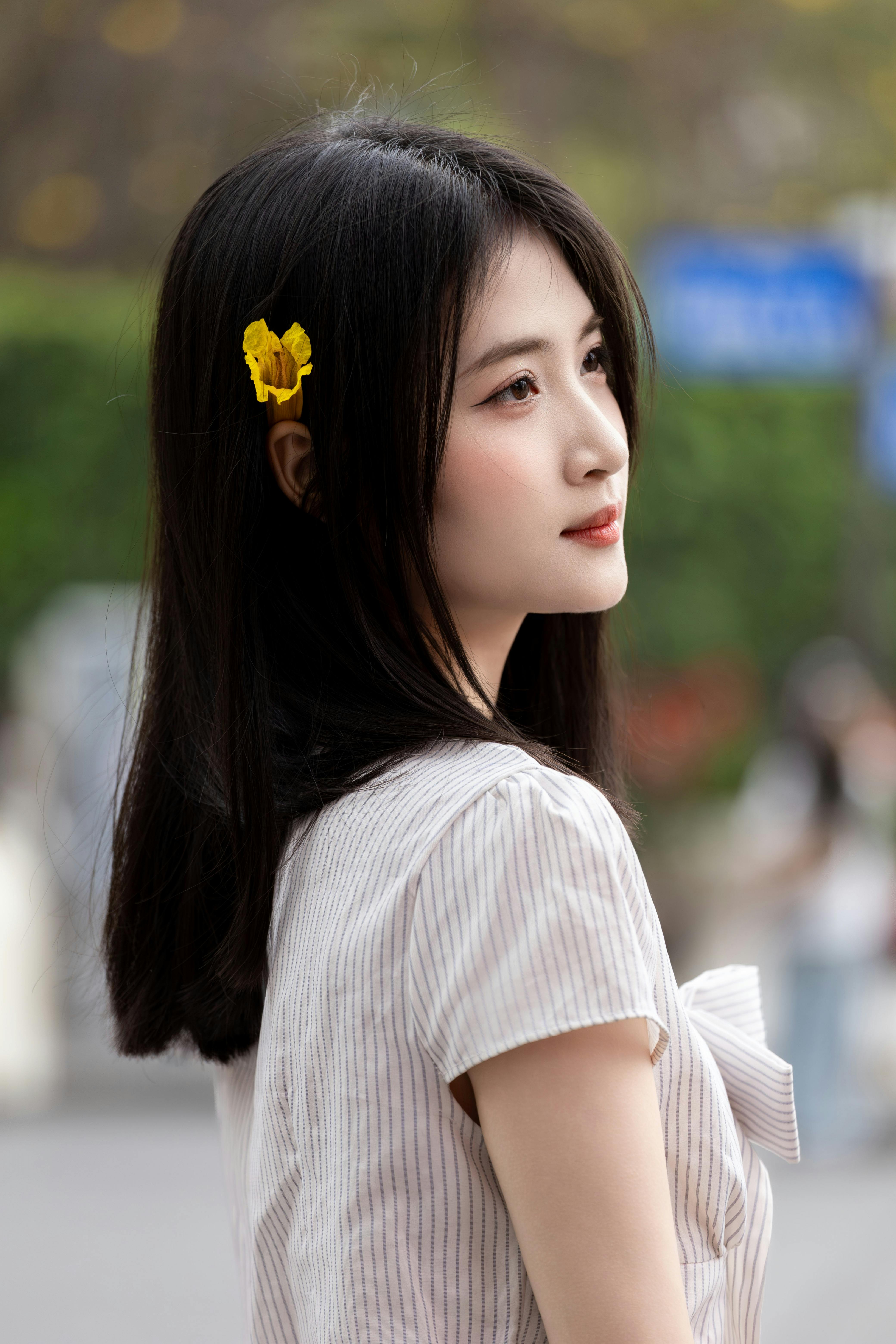 Side profile portrait of a young woman with a yellow flower in her hair, taken in Hà Nội, Việt Nam.