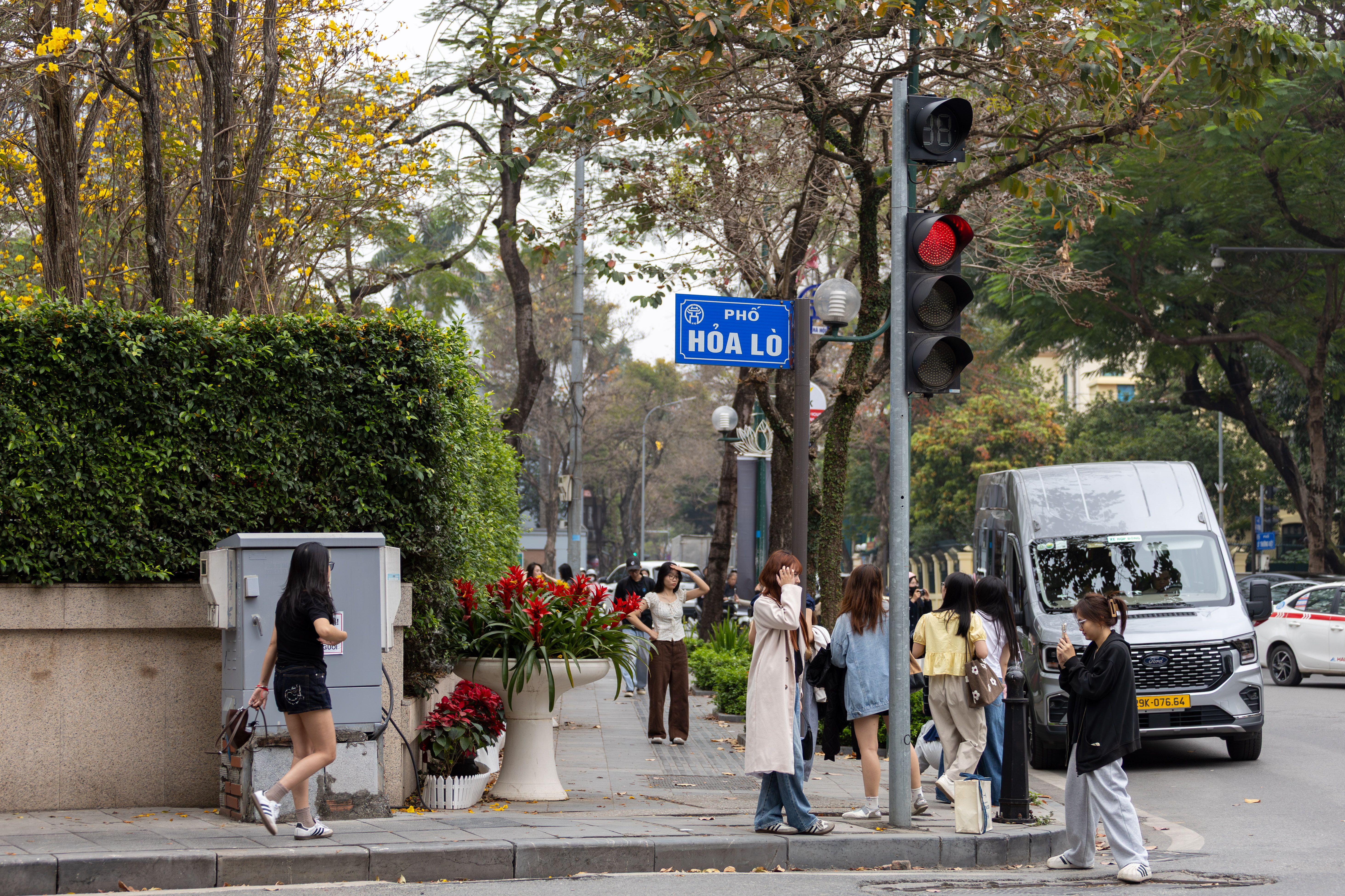 A lively daytime street scene at Phố Hỏa Lò in Hanoi, depicting pedestrians and urban life.