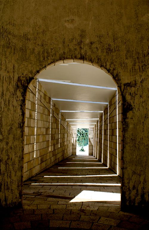 Free A captivating view of a stone tunnel with sunlight creating dramatic patterns through the archway. Stock Photo