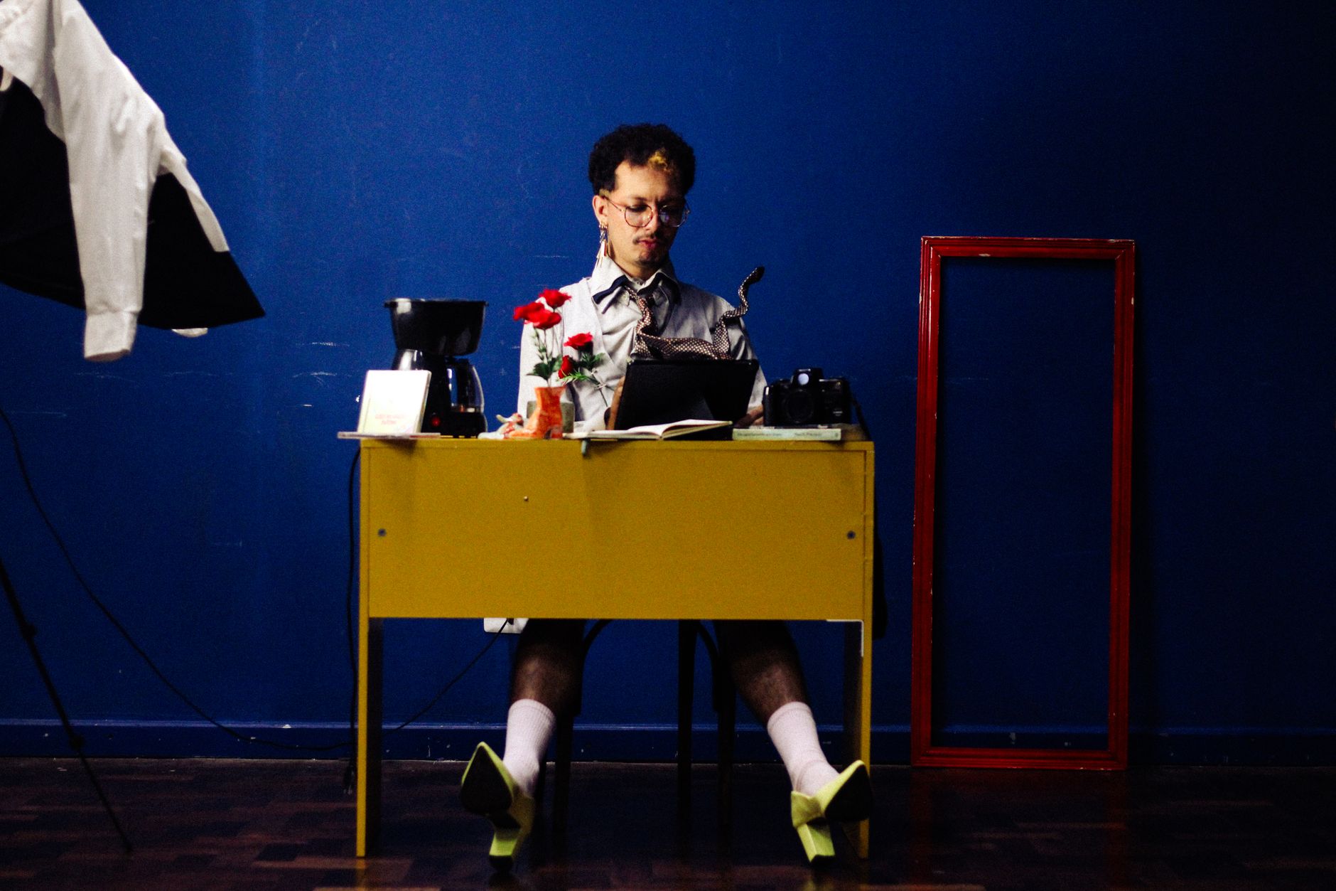 An artist immersed in work at a vibrant and colorful studio desk setup with unique decor.