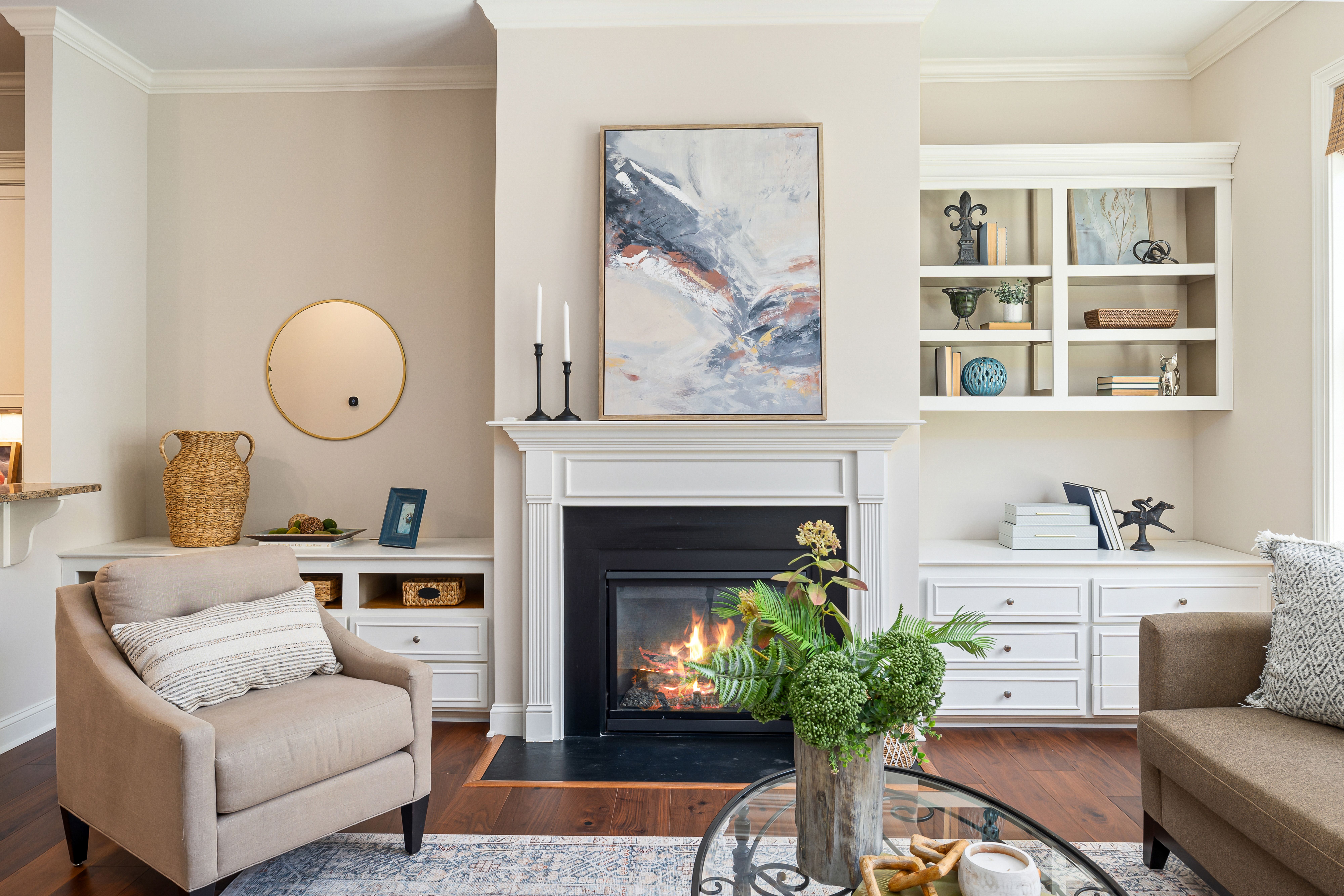 An elegant, cozy modern living room styled with a warm fireplace, neutral-colored furniture, and polished decor