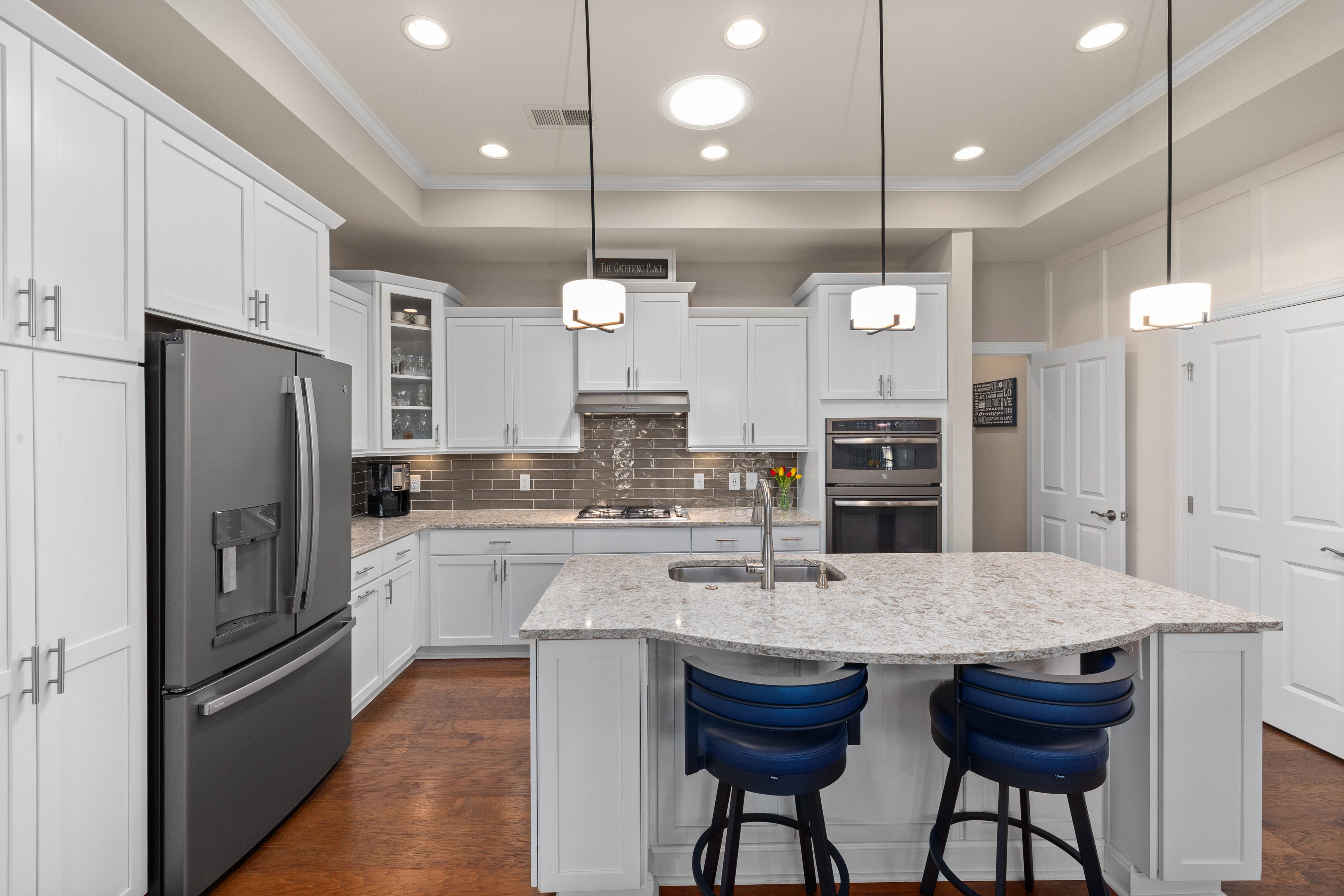 Elegant white kitchen renovation in Guelph featuring a marble island and stainless steel appliances.