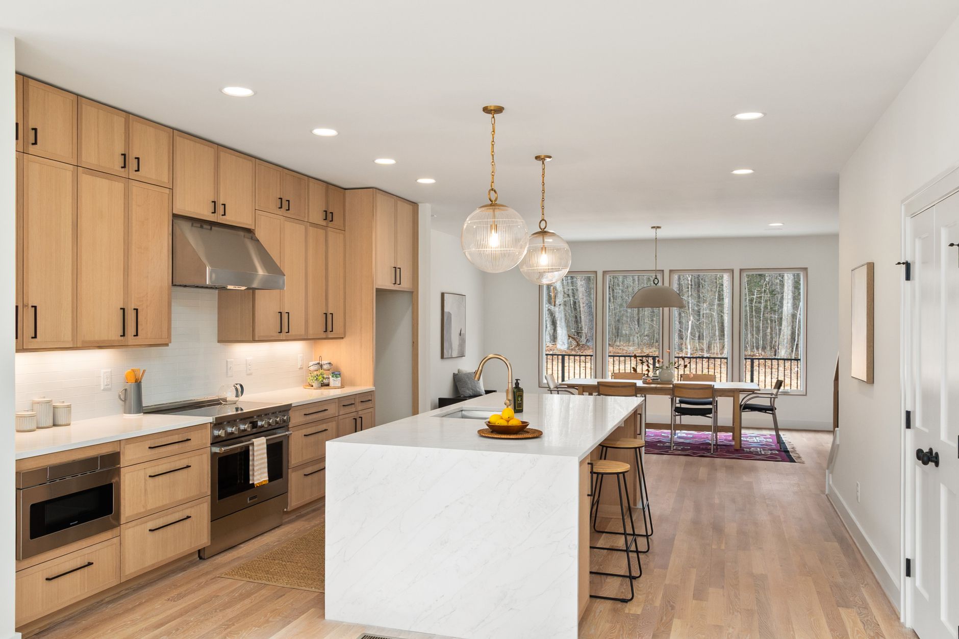 Open-concept kitchen with a marble island and painted perimeter cabinets — two-tone kitchen cabinet paint colors and pairings