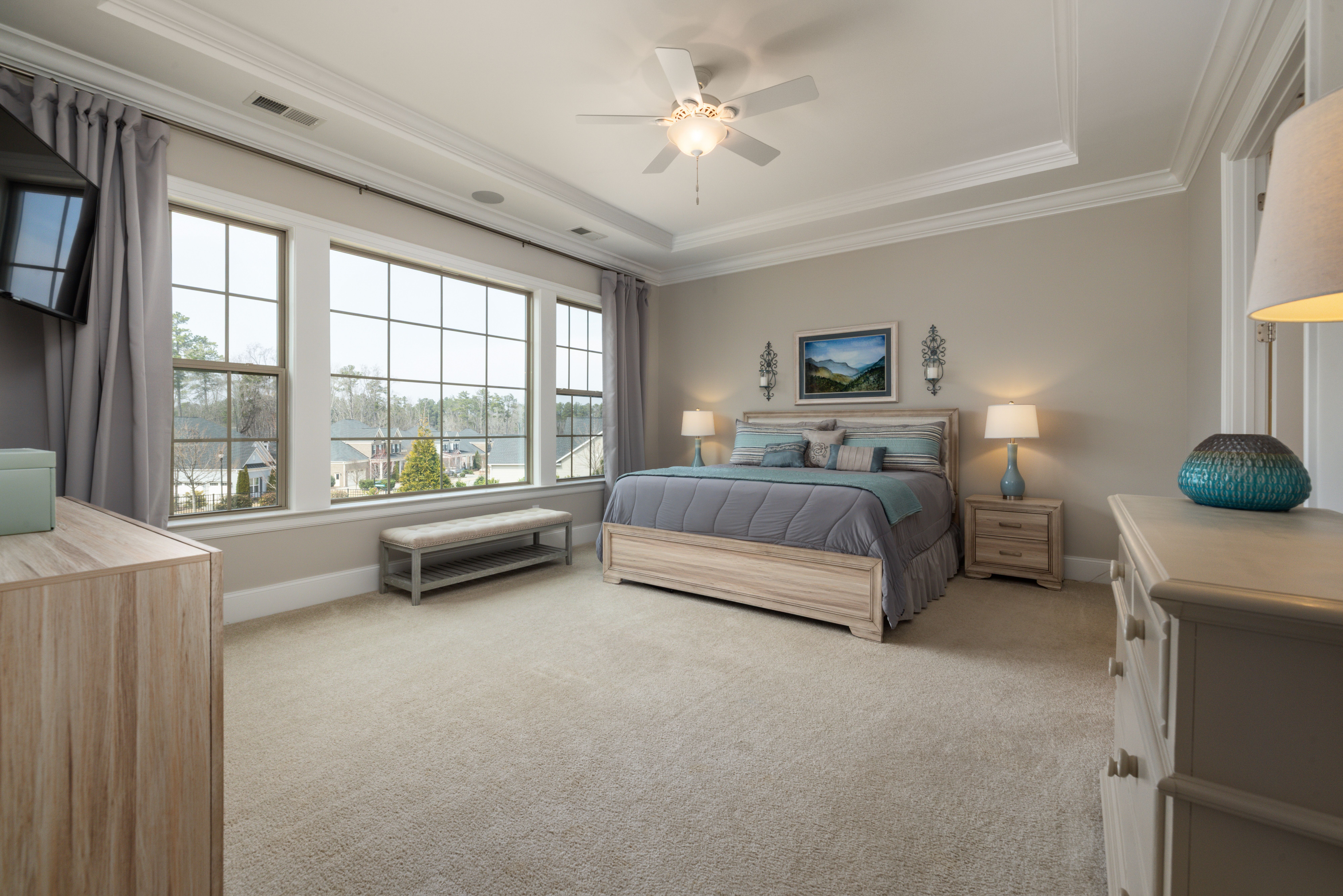 A modern bedroom with large windows, elegant decor, and neutral tones offering a cozy and bright atmosphere.