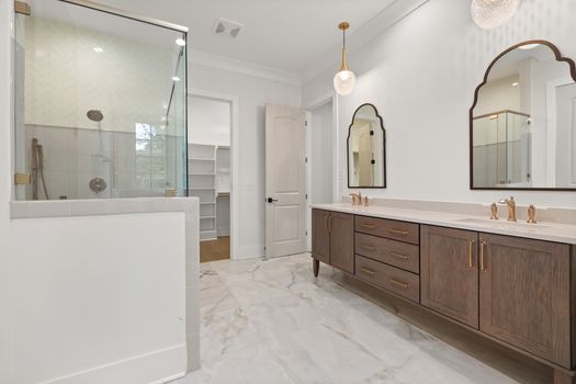 Spacious bathroom with a modern double vanity and glass shower, featuring elegant fixtures.