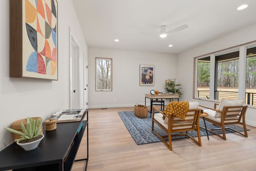 Stylish modern home office featuring wooden furniture, abstract art, and natural light through large windows.