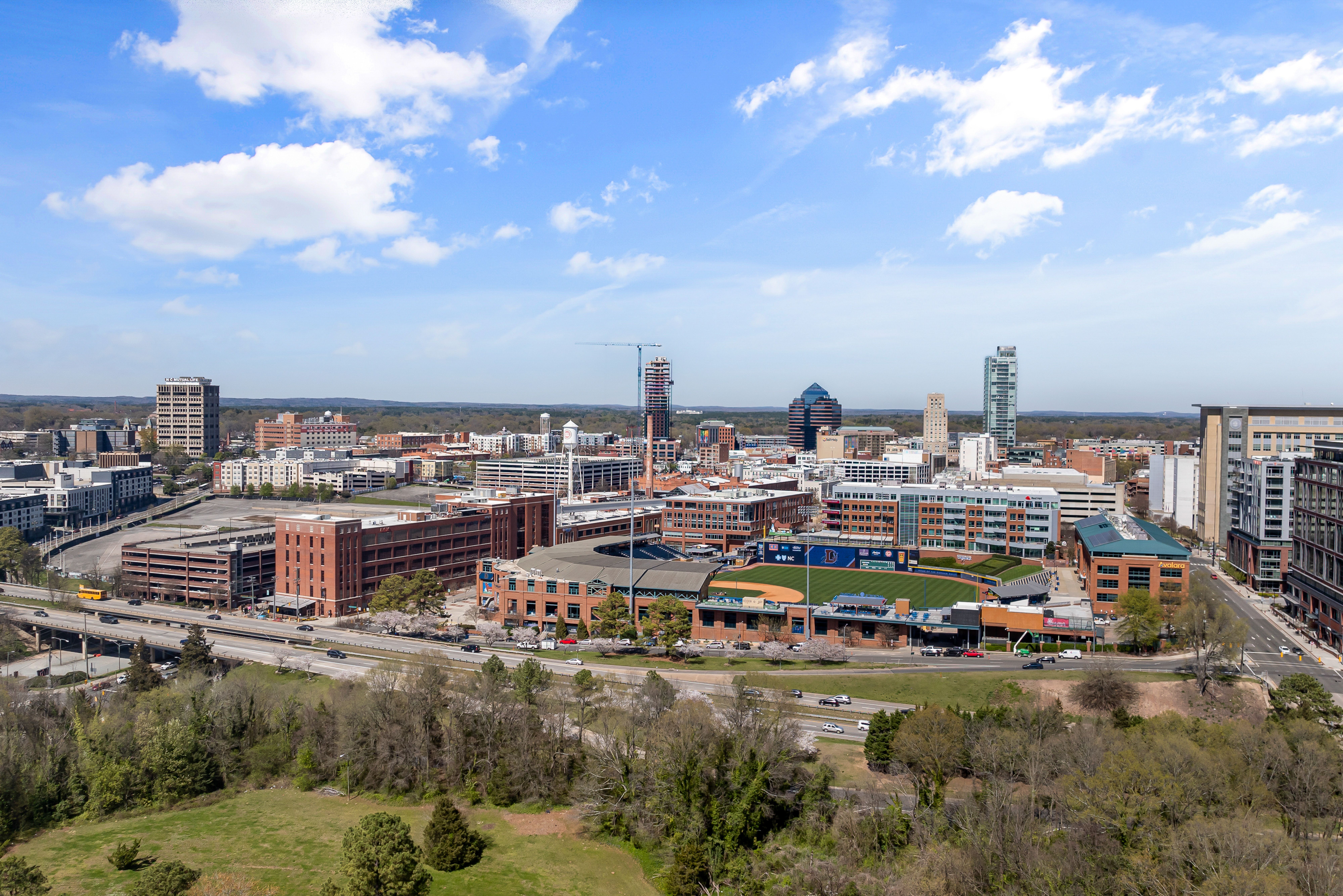 Aerial photo showing downtown Durham's vibrant skyline and cityscape on a sunny day.