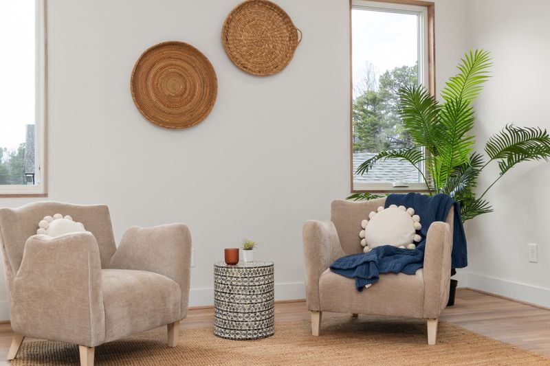 A comfortable counselling room with beige armchairs, a wicker vase and a potted plant in soft natural light