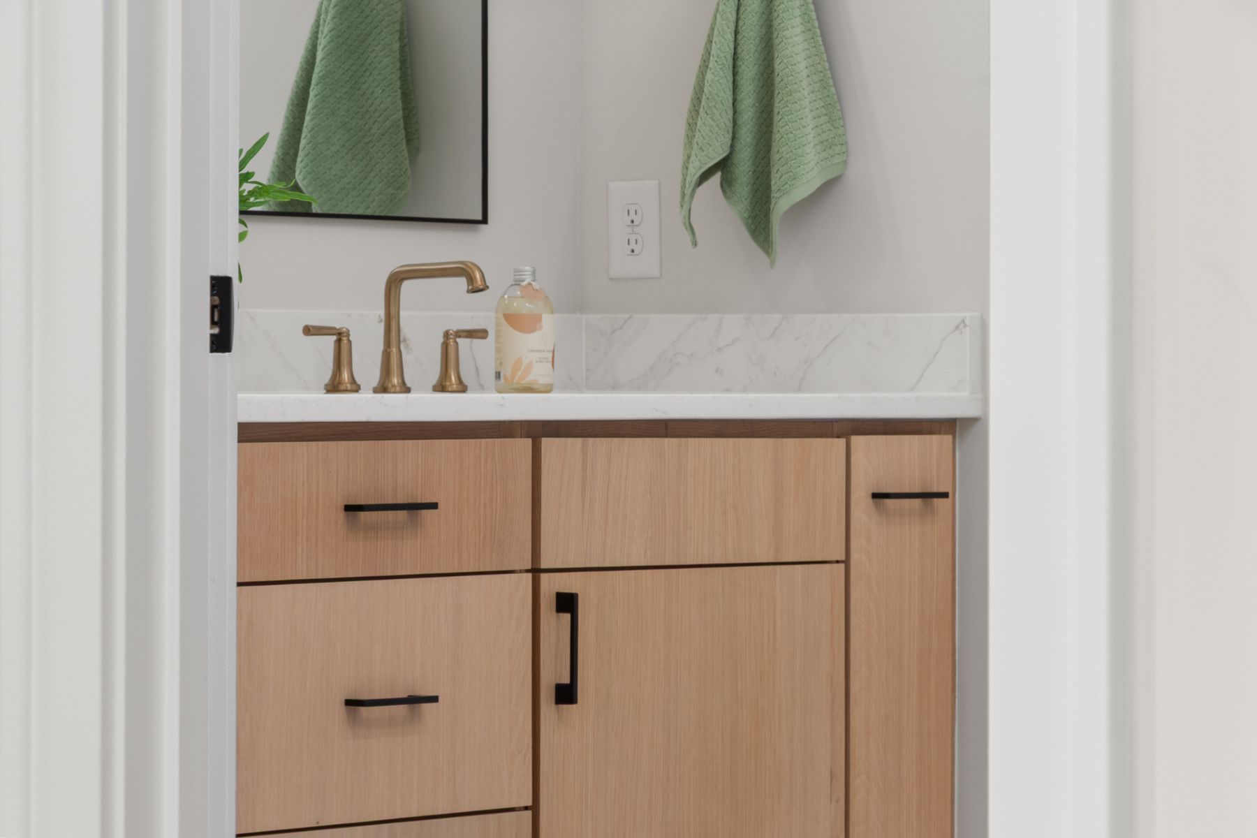 Bright bathroom with pale wood vanity, white sink and simple light surfaces