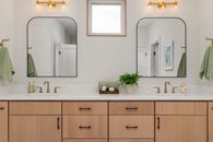 Elegant bathroom featuring double sinks, mirrors, and warm lighting. Modern design with wooden cabinetry.