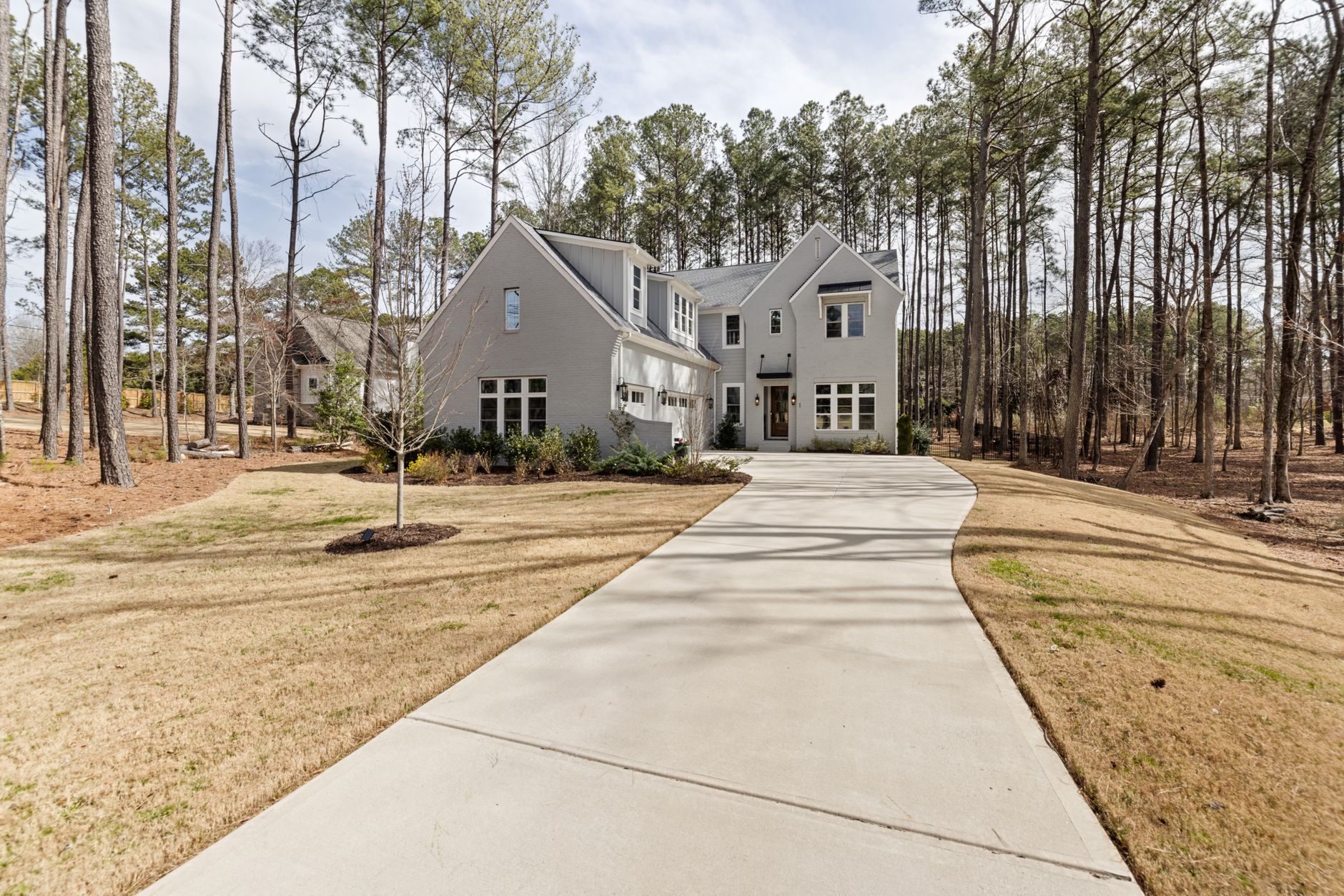 A stylish suburban house with a long driveway immersed in a peaceful wooded area.