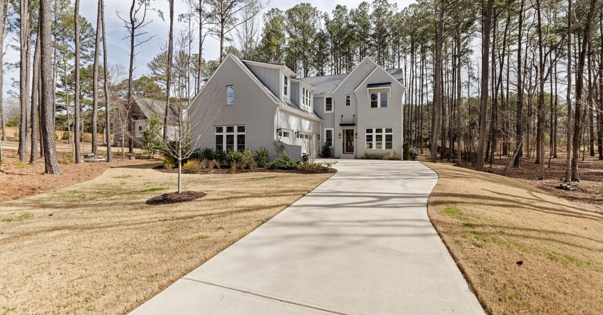 A stylish suburban house with a long driveway immersed in a peaceful wooded area.