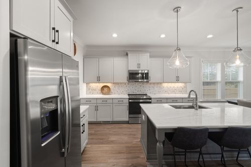 Free Sleek modern kitchen with stainless steel appliances and elegant pendant lighting. Stock Photo