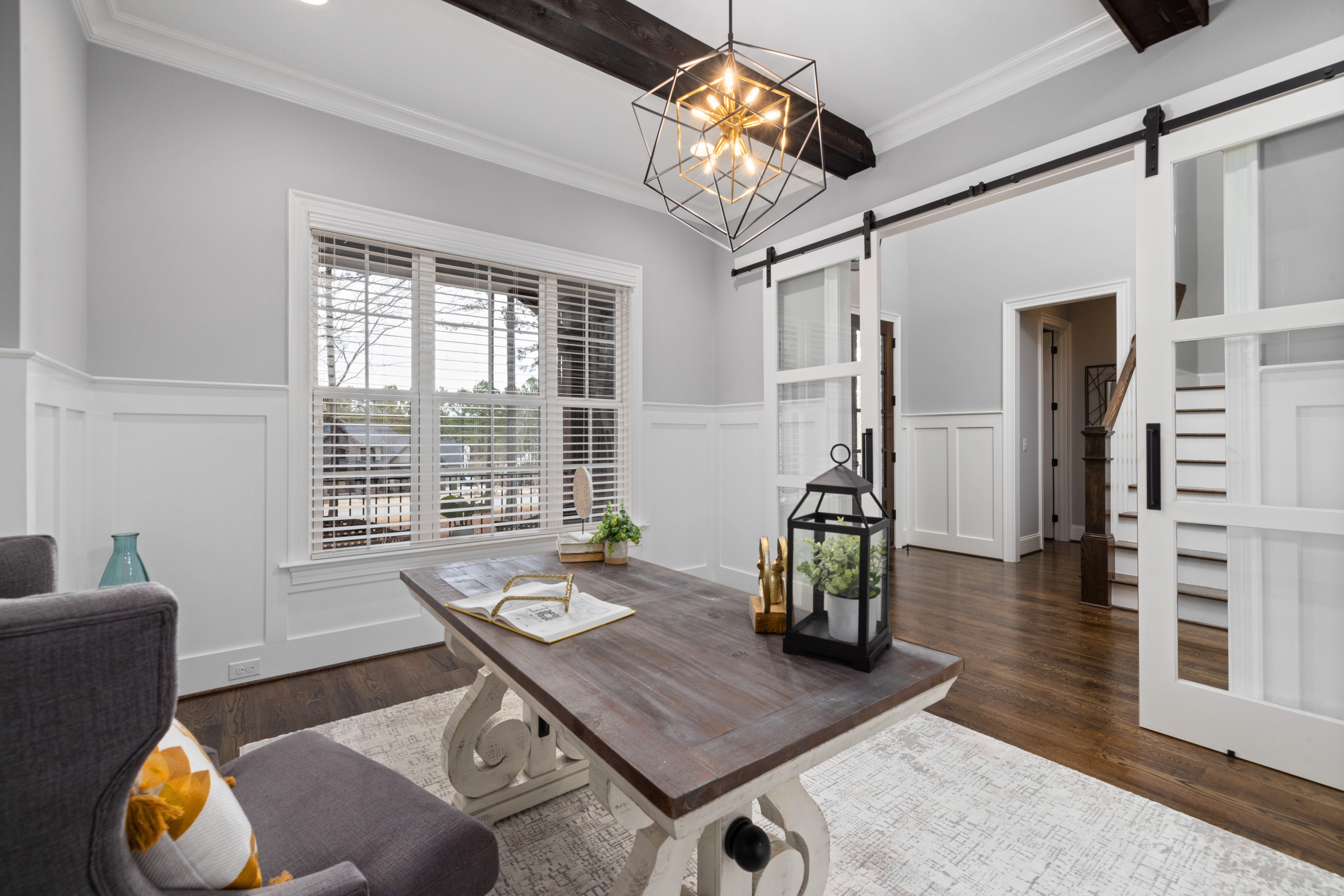Bright living room with modern decor, featuring a wooden table, lantern, and sliding barn doors.