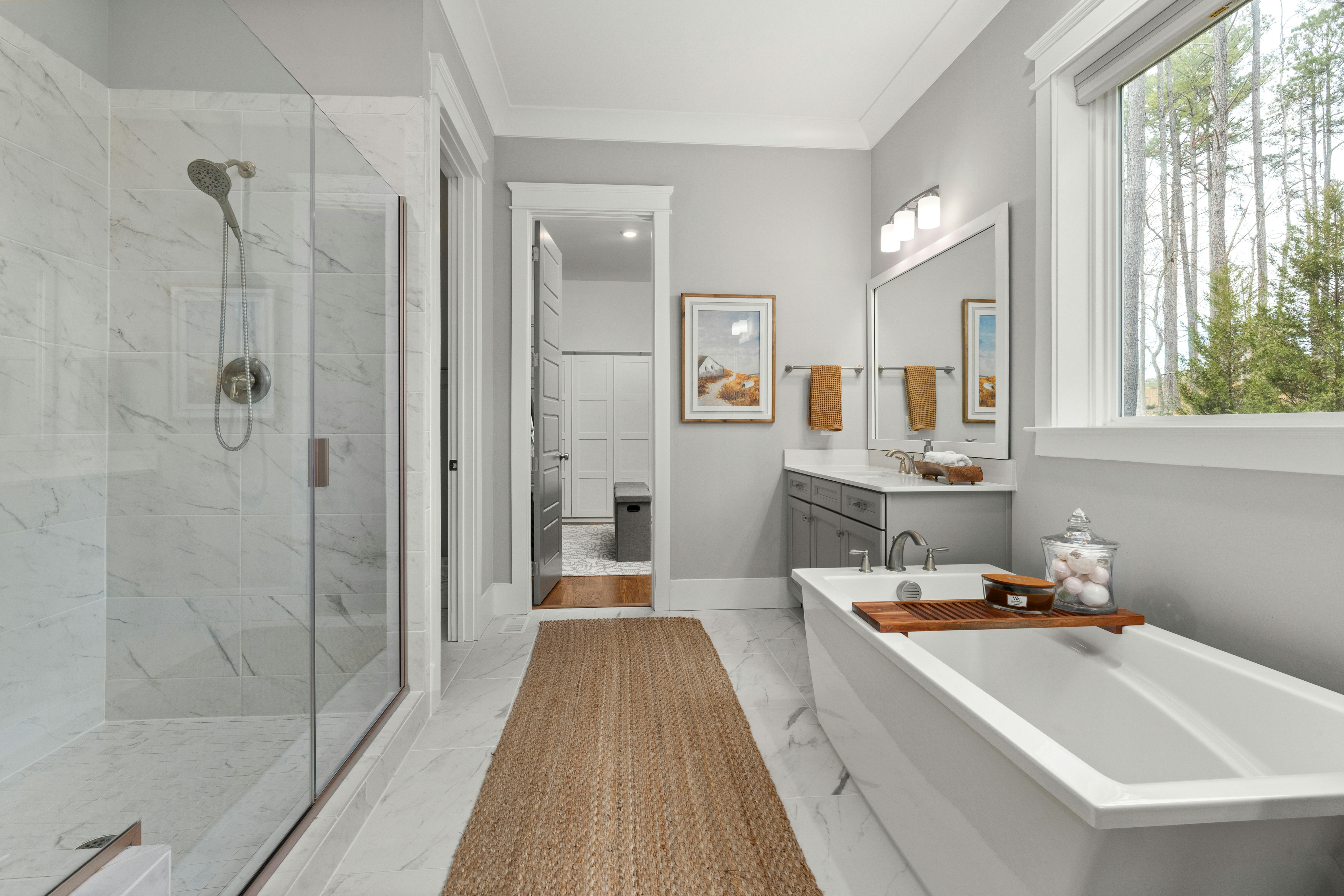 Elegant bathroom with a freestanding bathtub, glass shower, and large window view.