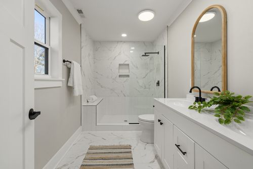 Free Bright modern bathroom featuring marble shower, large mirror, and sleek faucets. Stock Photo