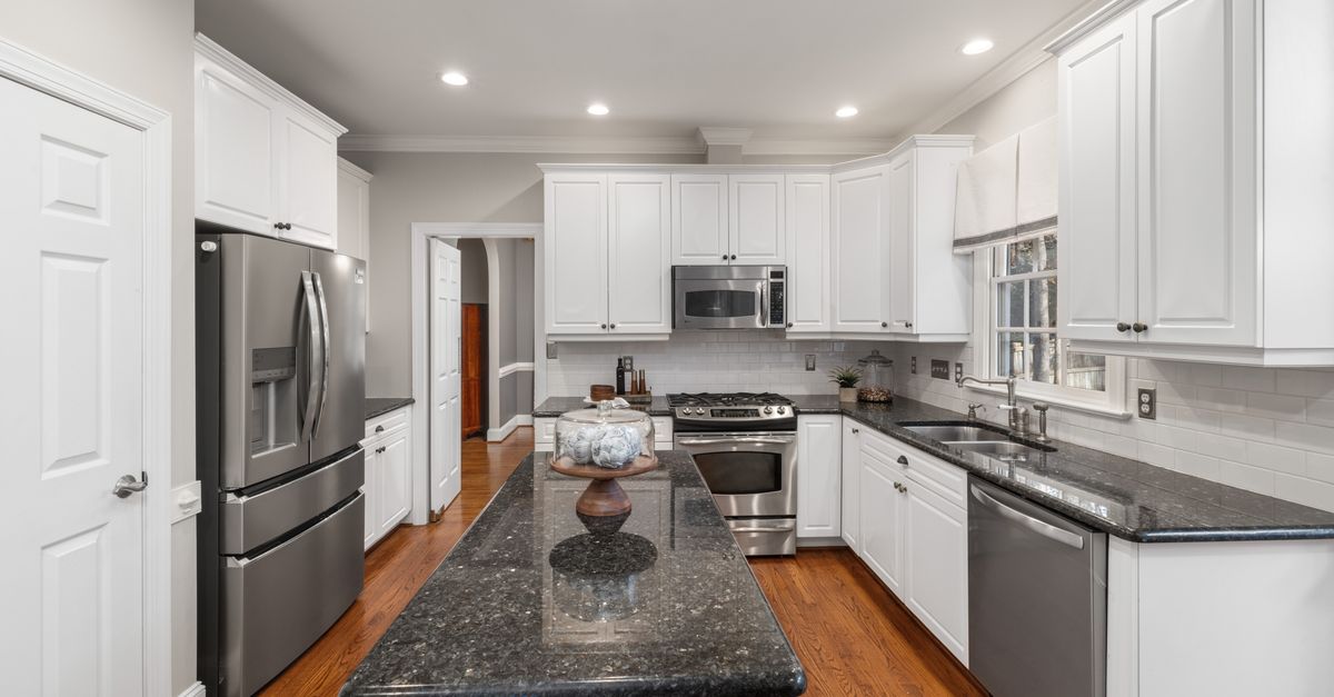 Sleek modern kitchen featuring granite countertops, stainless steel appliances, and bright white cabinets.