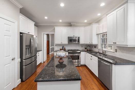 Sleek modern kitchen featuring granite countertops, stainless steel appliances, and bright white cabinets.