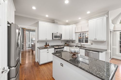 Free Bright kitchen with white cabinetry and granite countertops, showcasing modern appliances and wooden flooring. Stock Photo
