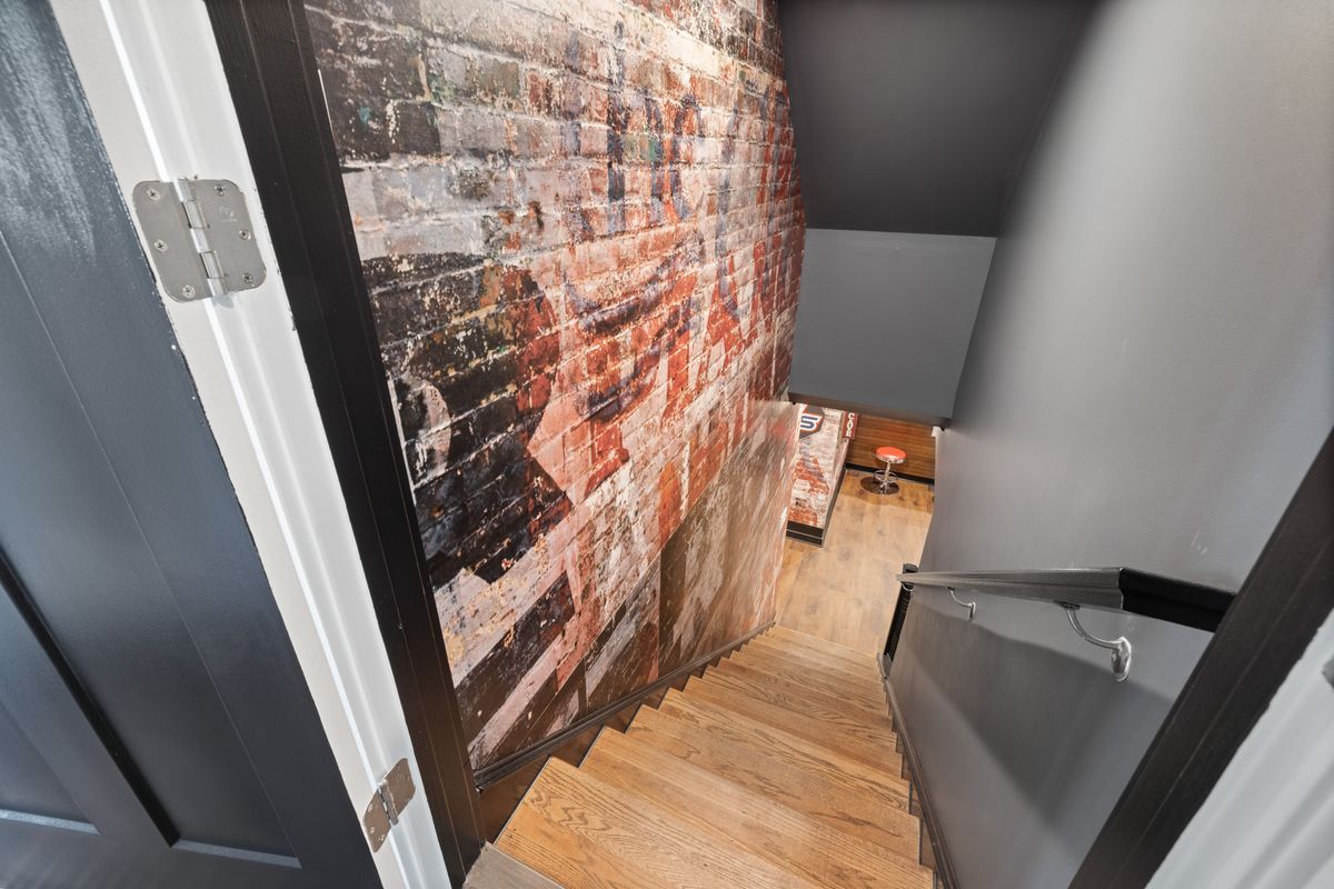 A modern staircase with exposed brick wall art leading to a stylish basement. Stock Photo.