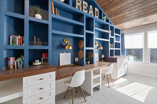 Free Bright home study room with custom blue bookshelves, wooden desk, and white chairs. Stock Photo