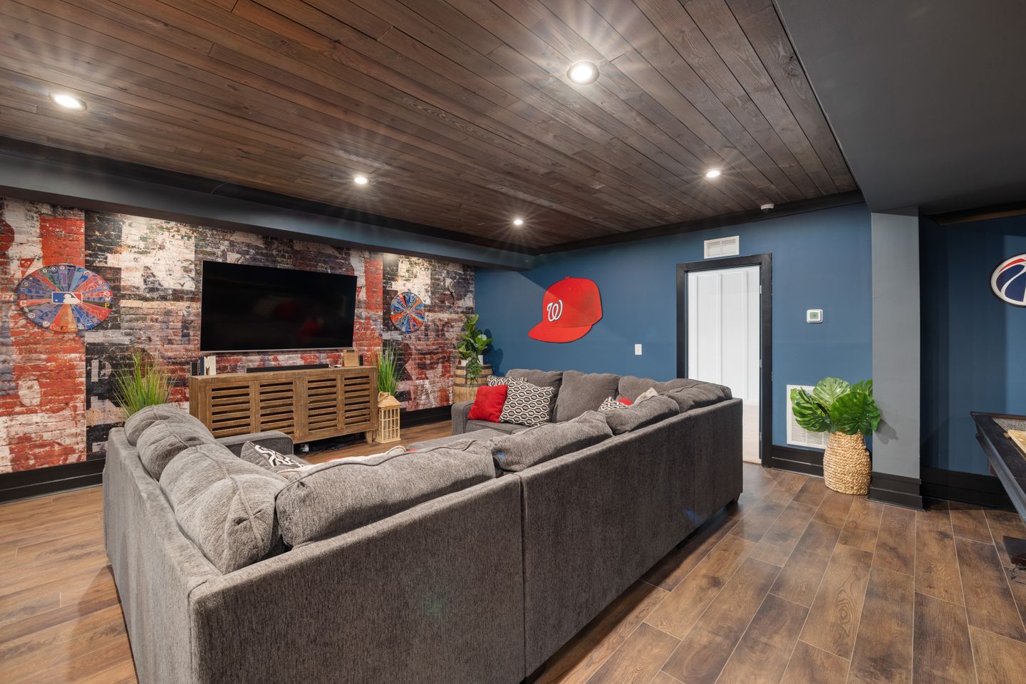 Spacious 2026 basement renovation in Ontario, featuring a stylish large couch and modern TV setup for summer entertainin Spacious 2026 basement renovation in Ontario, featuring a stylish large couch and modern TV setup for summer entertainin