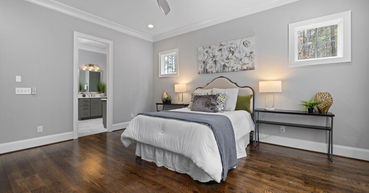 Spacious modern bedroom featuring neutral tones, elegant decor, and hardwood floors.