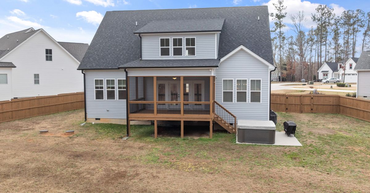 Two-story suburban home with wooden deck and fenced backyard, ideal for family living.