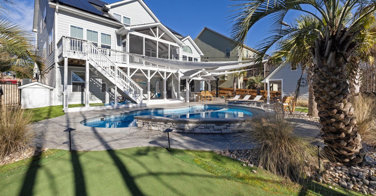 Sunny backyard with a pool and palm trees at a modern house, perfect for family leisure.