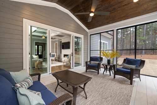 Free Sunlit enclosed porch with wicker furniture and views of lush greenery. Stock Photo