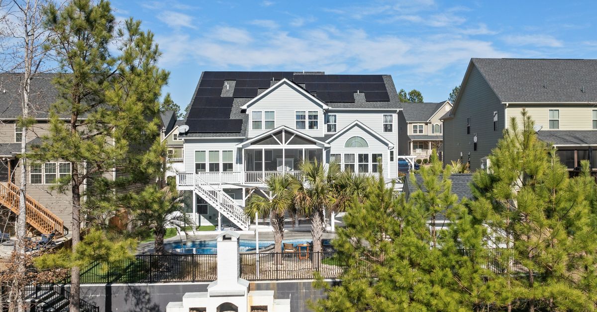 A stylish suburban home featuring solar panels and outdoor amenities under a clear blue sky.
