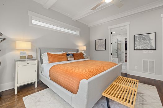 Cozy and modern bedroom interior featuring a plush bed with orange decor and elegant furnishings.