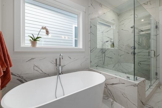 Elegant bathroom with marble tiles, a glass shower, and freestanding tub.