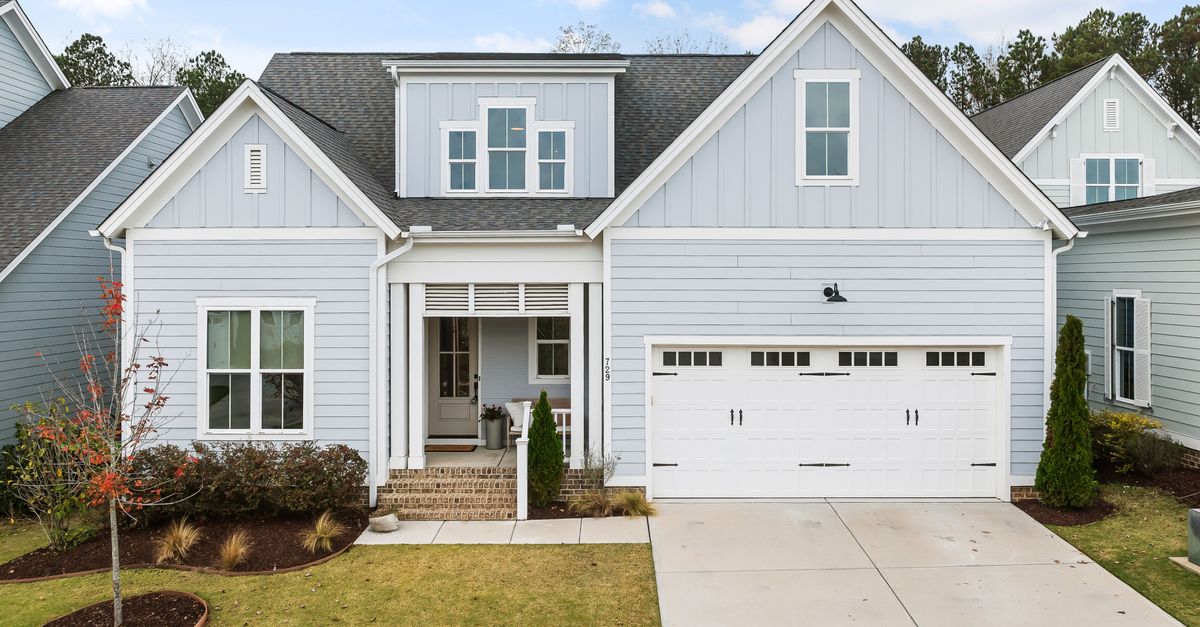 A stylish suburban house with a white garage and a neat front yard, showcasing contemporary architecture.