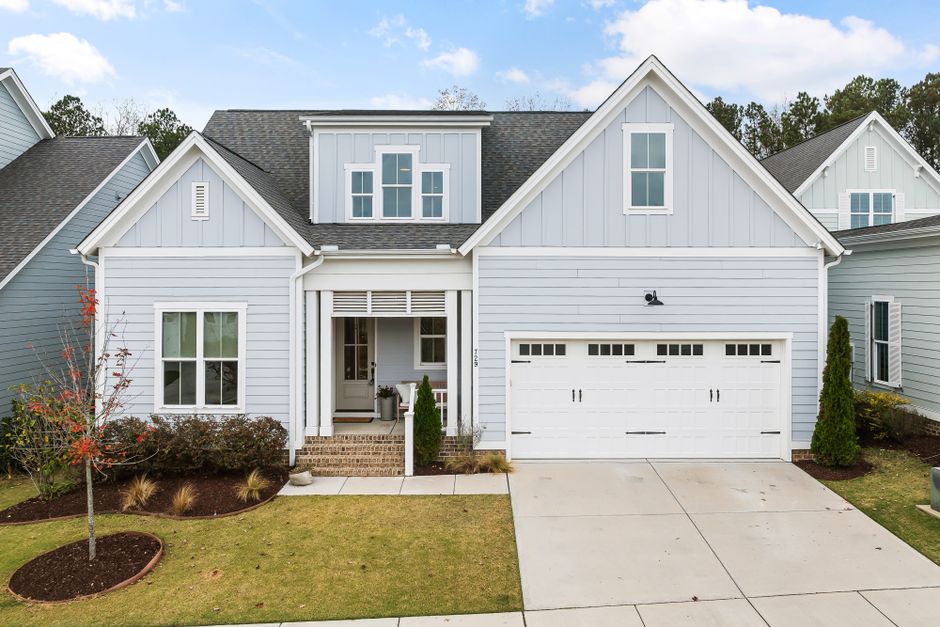 A stylish suburban house with a white garage and a neat front yard, showcasing contemporary architecture.