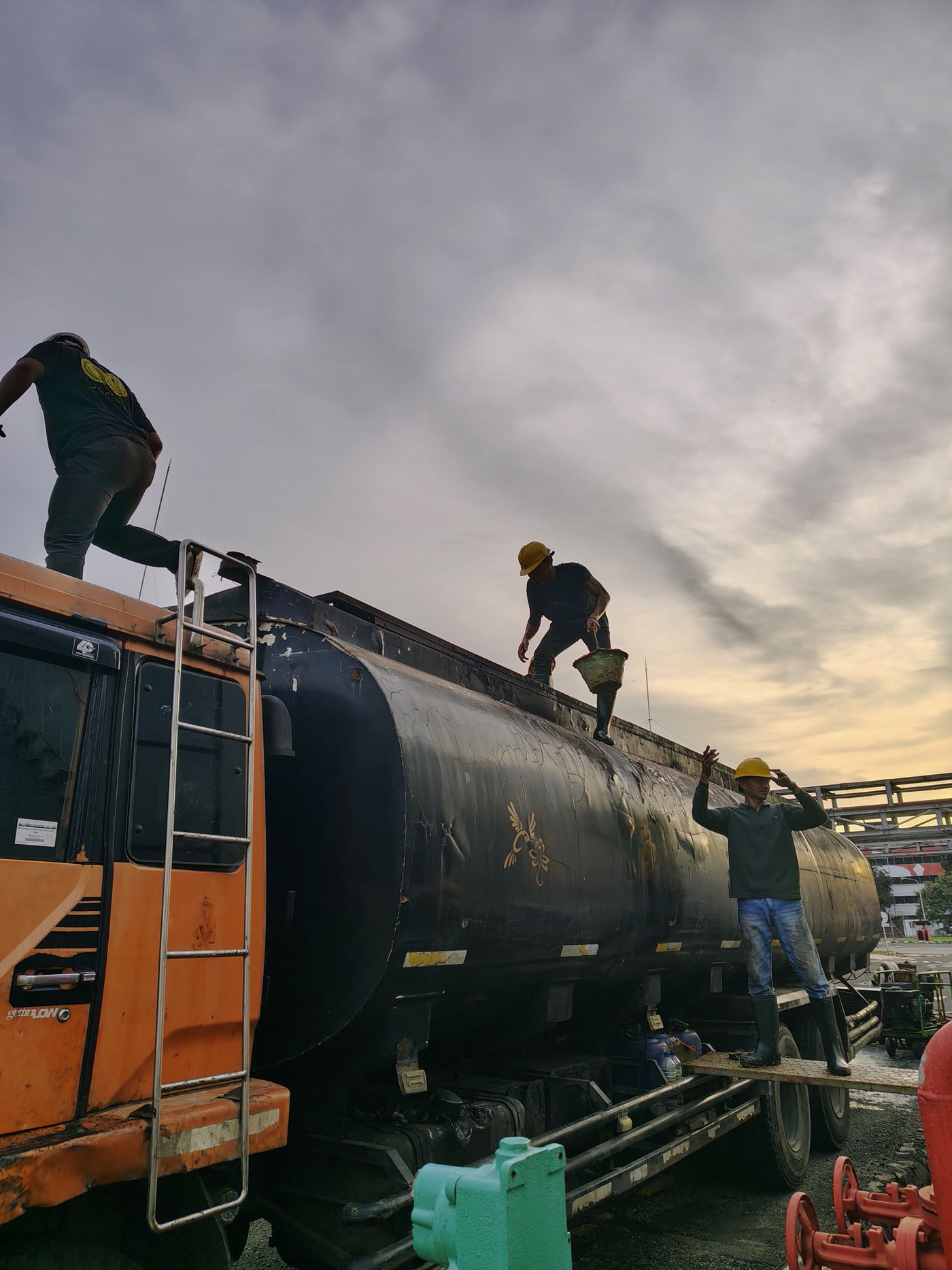 Oilfield workers using an industrial ladder at dusk