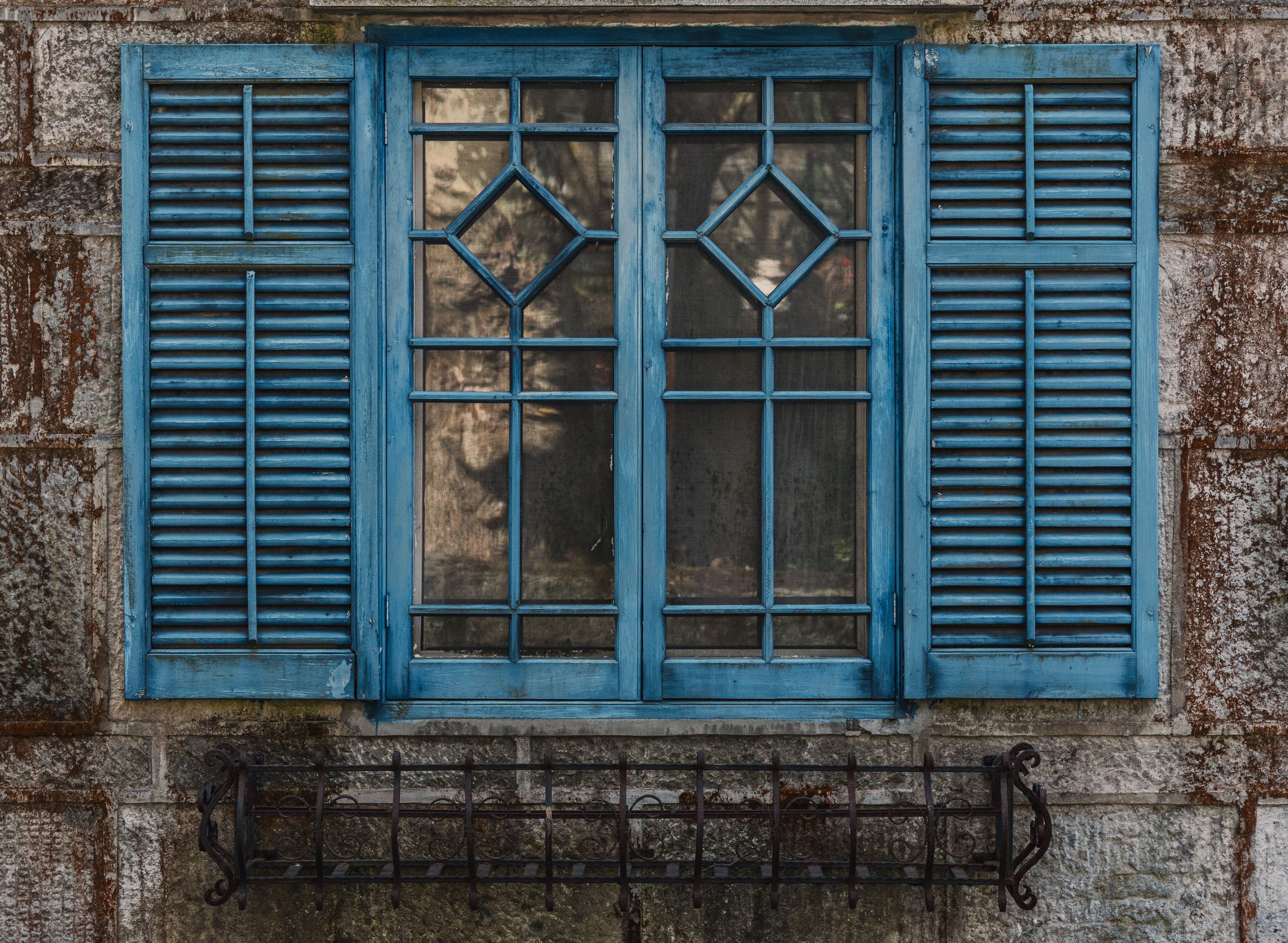 Charming rustic blue window shutters on a textured stone wall, perfect for vintage design inspiration.